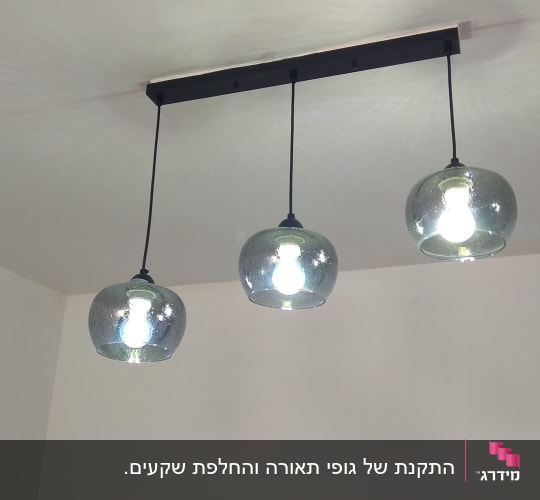 שלושה גופי תאורה תלויים עם נורות דולקות